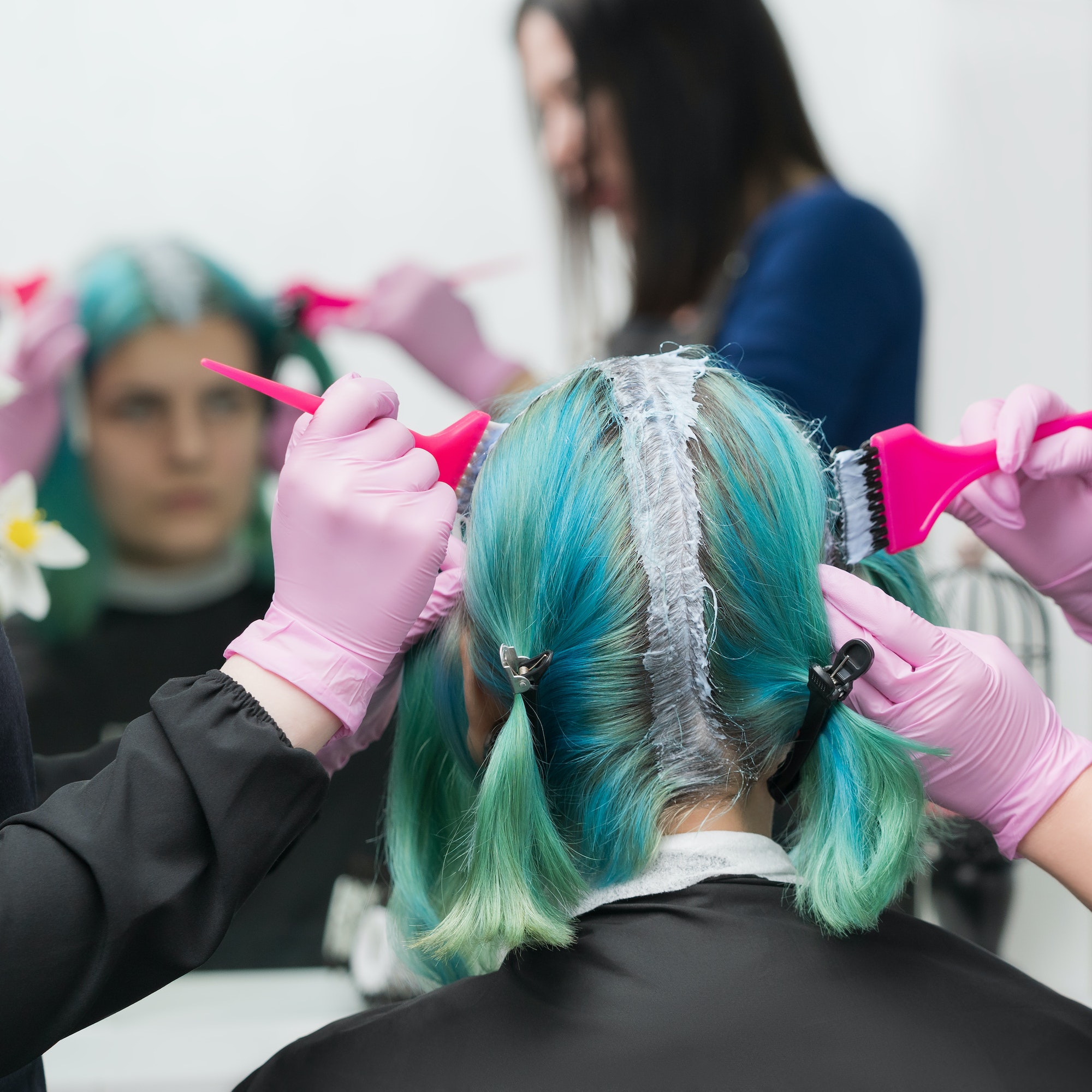 Process of hair dyeing in salon. Two hairdressers applying paint to hair during bleaching hair roots